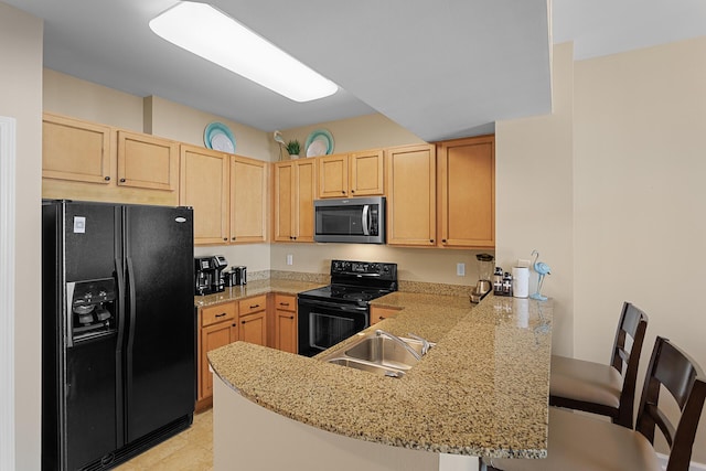 kitchen with sink, light stone counters, black appliances, light brown cabinetry, and kitchen peninsula