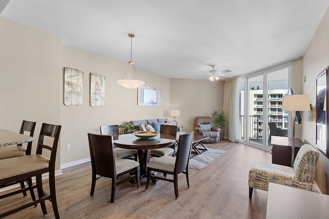 dining area with expansive windows, ceiling fan, and light wood-type flooring