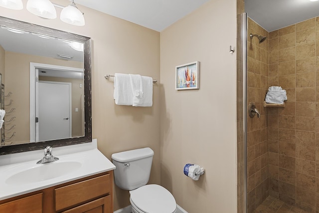 bathroom featuring vanity, toilet, and a tile shower