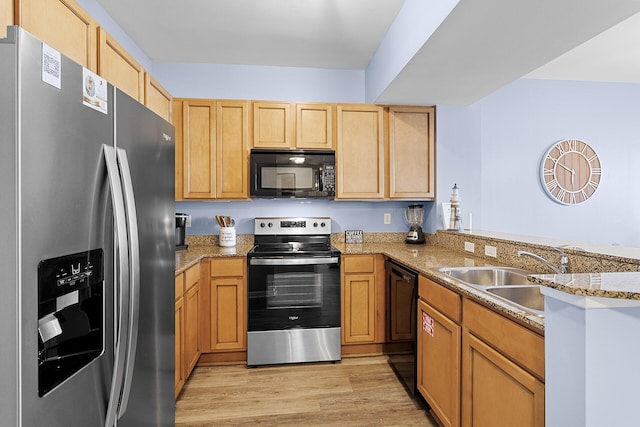 kitchen with sink, light wood-type flooring, kitchen peninsula, light stone countertops, and black appliances