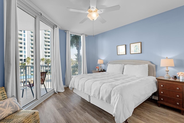 bedroom with hardwood / wood-style floors, multiple windows, and access to outside