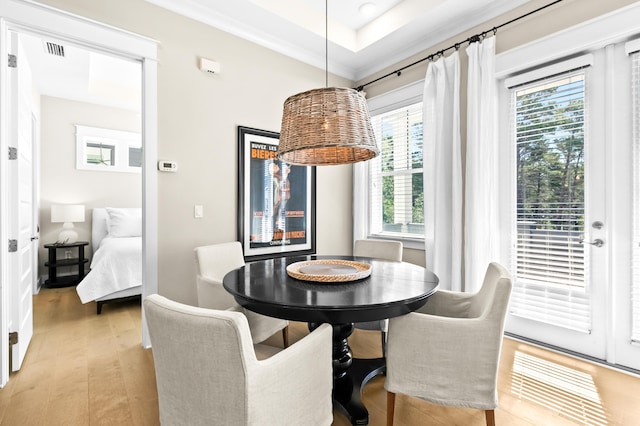 dining space featuring light wood-type flooring, a raised ceiling, and a wealth of natural light