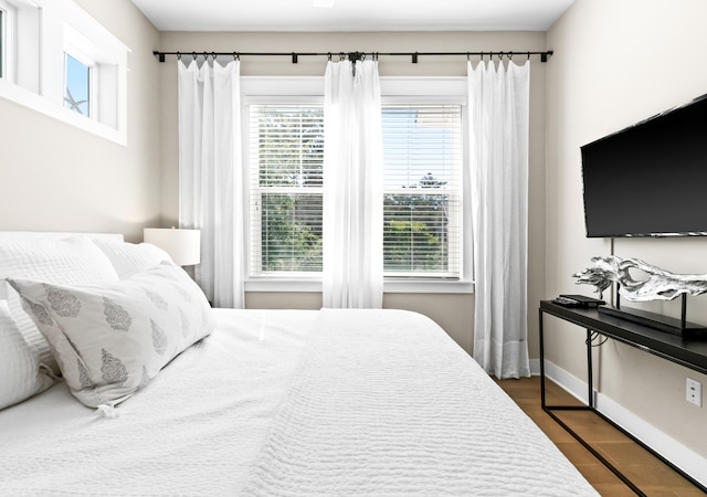 bedroom with dark hardwood / wood-style flooring and multiple windows