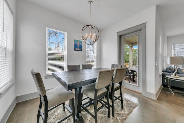 dining area with wood-type flooring, an inviting chandelier, and a wealth of natural light