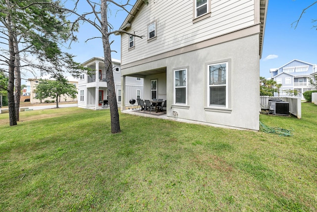 rear view of house with cooling unit, a patio area, and a lawn