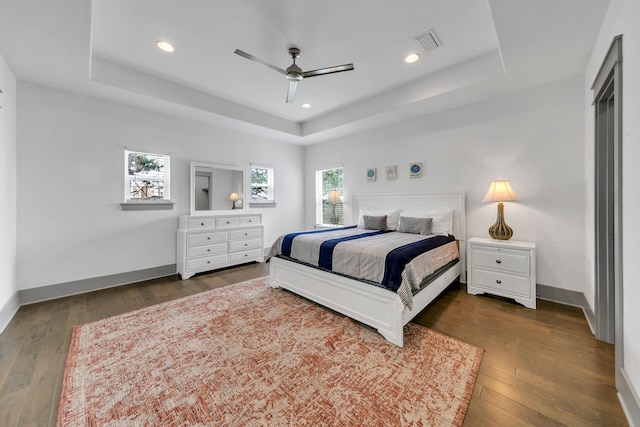 bedroom with a raised ceiling, ceiling fan, and dark hardwood / wood-style floors