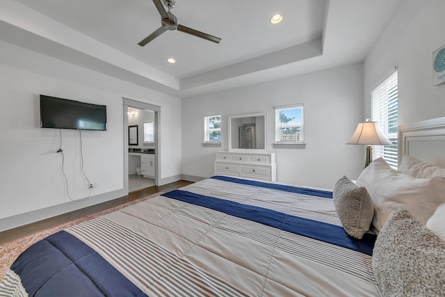 bedroom with hardwood / wood-style flooring, ceiling fan, connected bathroom, and a tray ceiling