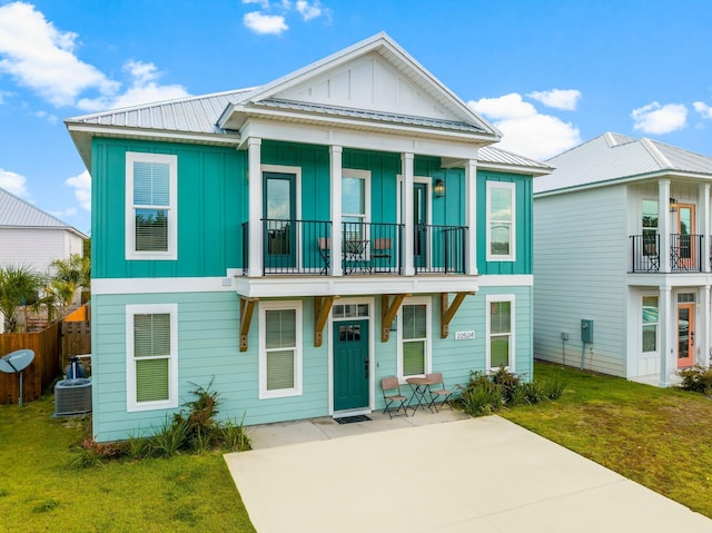 view of front facade featuring a balcony, a front yard, and cooling unit