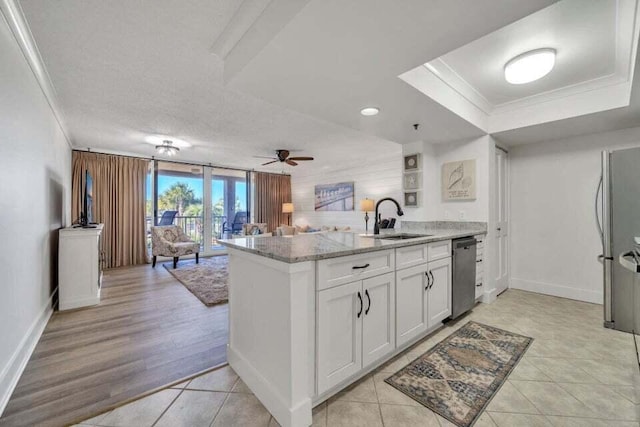 kitchen featuring kitchen peninsula, light stone counters, white cabinets, stainless steel dishwasher, and sink