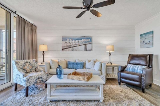 living room featuring wood-type flooring, a textured ceiling, ceiling fan, and plenty of natural light