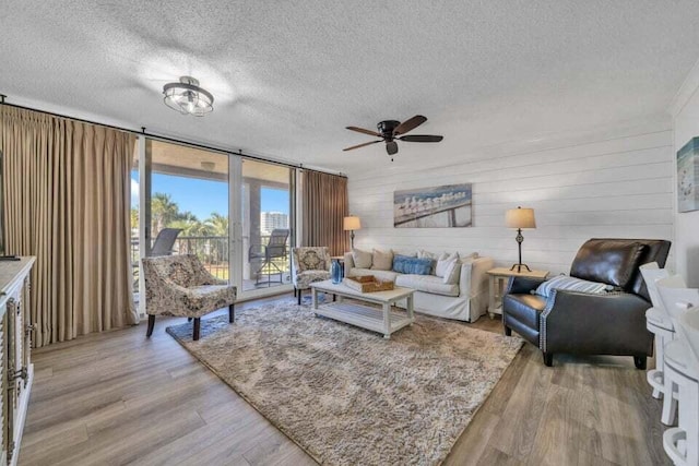 living room featuring a textured ceiling, ceiling fan, light hardwood / wood-style floors, and expansive windows