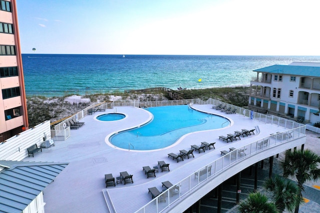 view of swimming pool featuring a community hot tub, a view of the beach, and a water view