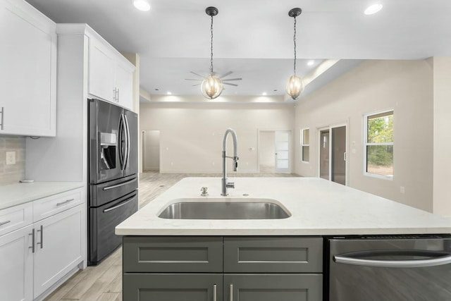 kitchen with sink, stainless steel appliances, an island with sink, and white cabinetry