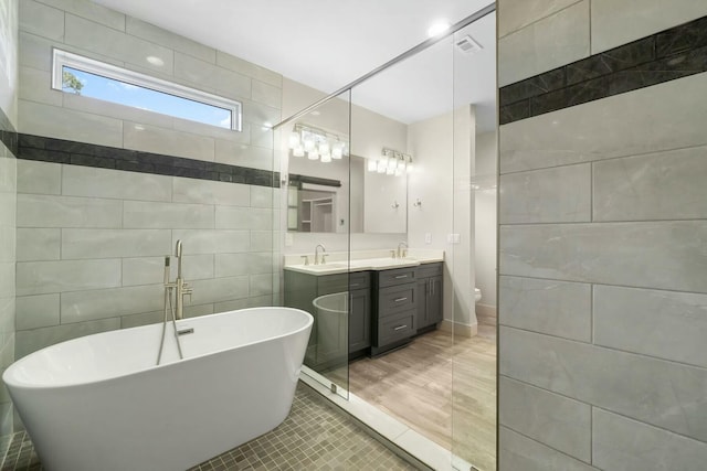 full bathroom with toilet, tile patterned flooring, tile walls, and vanity