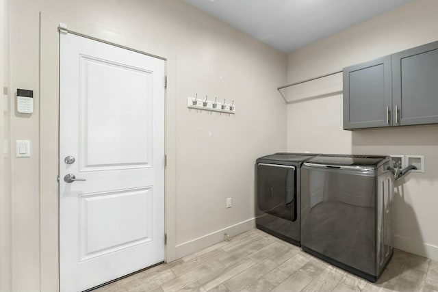 washroom featuring light hardwood / wood-style floors, cabinets, and washing machine and clothes dryer