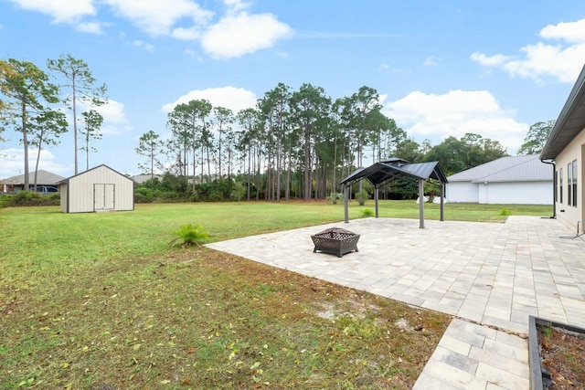 view of yard with a gazebo, a fire pit, a storage unit, and a patio area