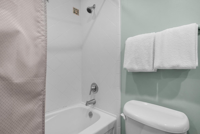 bathroom with tiled shower / bath combo and toilet