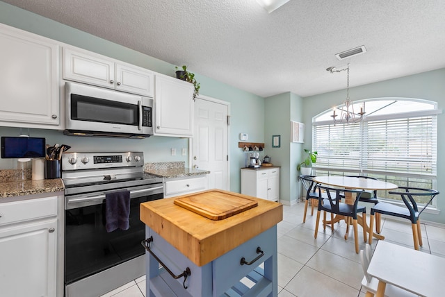 kitchen featuring white cabinetry, light tile patterned flooring, a textured ceiling, a chandelier, and stainless steel appliances