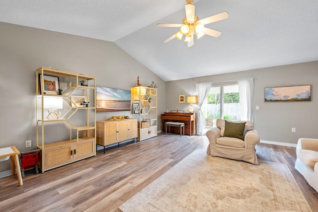 living room featuring ceiling fan, hardwood / wood-style floors, a textured ceiling, and vaulted ceiling