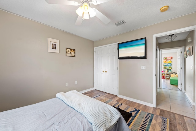 bedroom featuring ceiling fan, hardwood / wood-style floors, a closet, and a textured ceiling