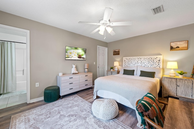 bedroom with a textured ceiling, dark wood-type flooring, ensuite bathroom, and ceiling fan