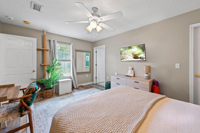 bedroom with ceiling fan, light hardwood / wood-style flooring, and a textured ceiling