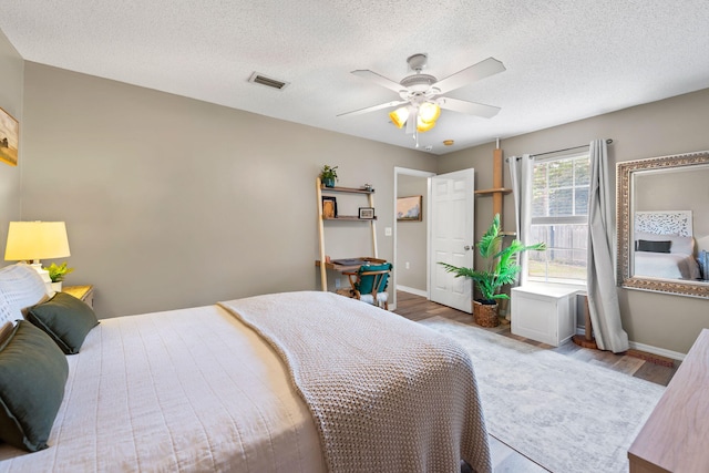 bedroom with ceiling fan, a textured ceiling, and light wood-type flooring