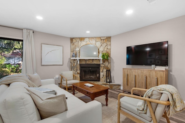 living room featuring a stone fireplace and hardwood / wood-style floors