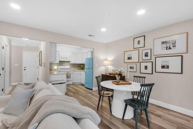 interior space with white cabinetry, white appliances, light hardwood / wood-style flooring, and backsplash