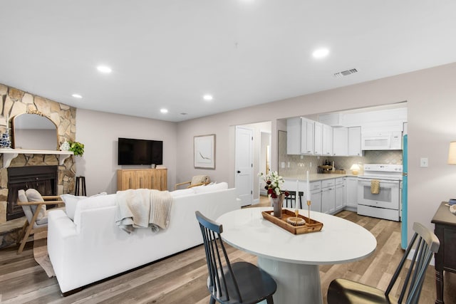 dining space featuring a stone fireplace and light hardwood / wood-style flooring