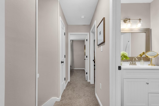 corridor with sink and light carpet