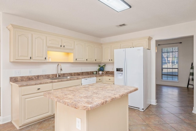 kitchen featuring sink, white appliances, light tile patterned floors, cream cabinets, and a kitchen island