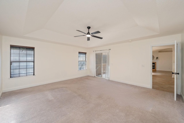 carpeted spare room featuring ceiling fan and a tray ceiling