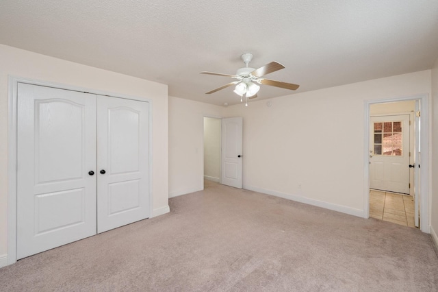 unfurnished bedroom featuring light carpet, ceiling fan, a closet, and a textured ceiling