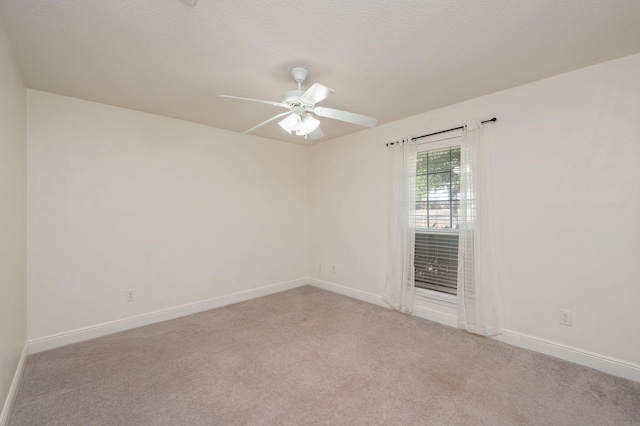 spare room featuring light colored carpet, a textured ceiling, and ceiling fan