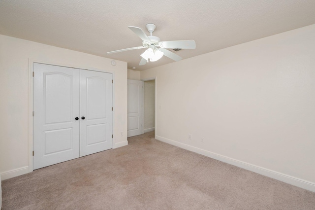 unfurnished bedroom featuring ceiling fan, light colored carpet, a closet, and a textured ceiling