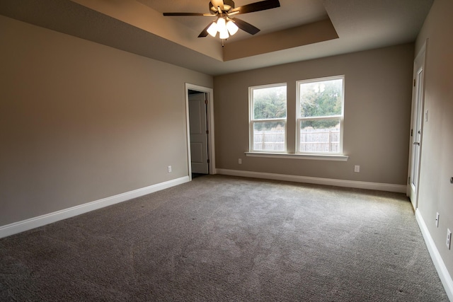 carpeted spare room featuring a tray ceiling and ceiling fan