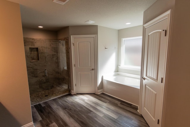 bathroom with shower with separate bathtub, hardwood / wood-style floors, and a textured ceiling