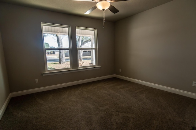 spare room featuring dark carpet and ceiling fan