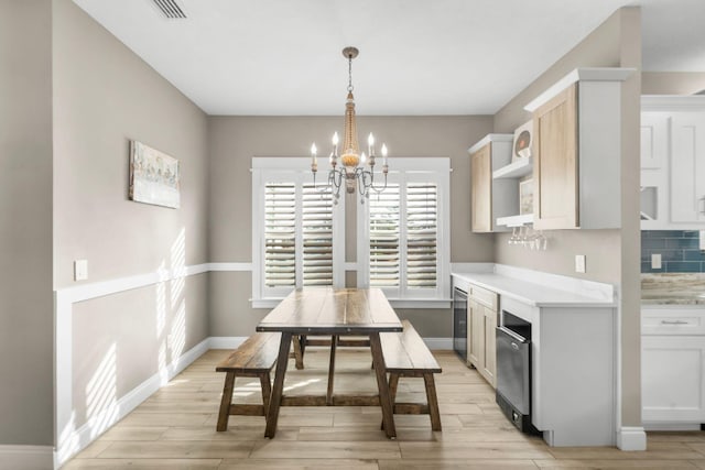 dining area with light wood-type flooring, a notable chandelier, and wine cooler