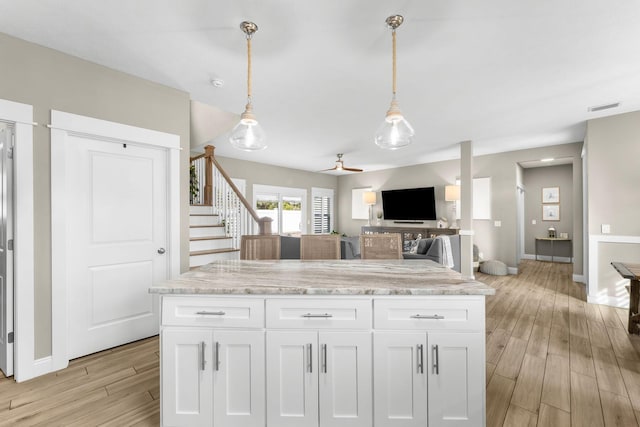 kitchen featuring ceiling fan, hanging light fixtures, white cabinetry, and light stone counters