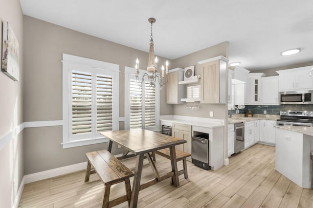 kitchen featuring a chandelier, stainless steel appliances, pendant lighting, white cabinets, and light hardwood / wood-style flooring