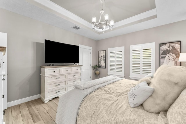 bedroom featuring a raised ceiling, light hardwood / wood-style flooring, and a chandelier