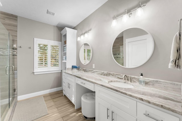 bathroom featuring a shower with door and vanity