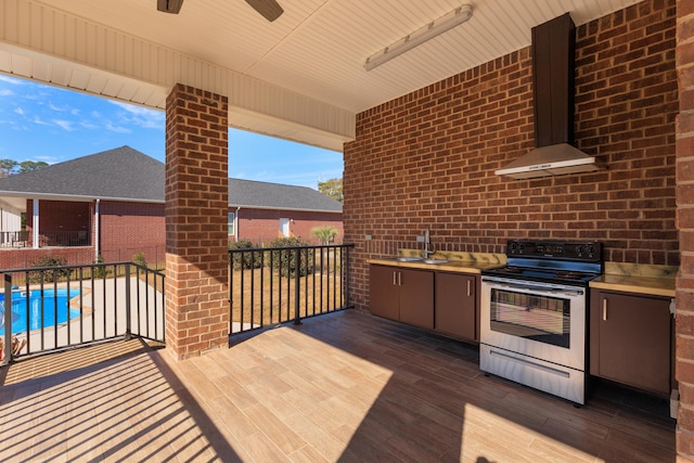 wooden terrace featuring sink, ceiling fan, a fenced in pool, and exterior kitchen