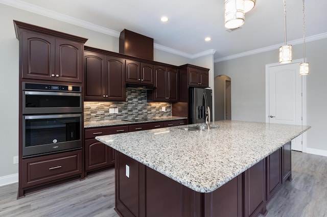 kitchen with sink, stainless steel appliances, a kitchen island with sink, and dark brown cabinetry