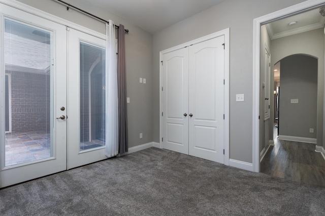 entryway with french doors, crown molding, and dark carpet