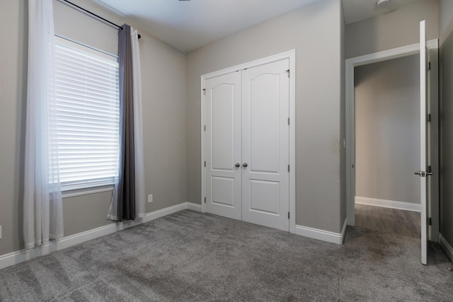 unfurnished bedroom with dark carpet and a closet