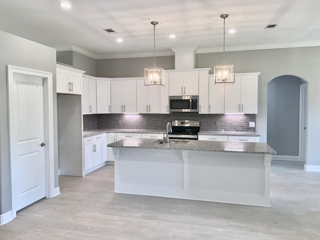 kitchen featuring a center island with sink, white cabinetry, hanging light fixtures, and appliances with stainless steel finishes