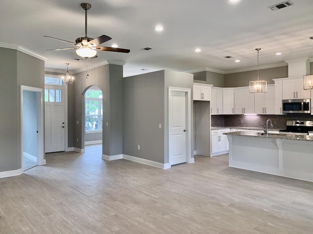 kitchen with light stone counters, stainless steel appliances, light hardwood / wood-style flooring, and white cabinetry